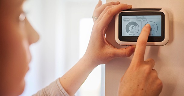 Woman touching her smart thermostat and reading how her energy consumption has gone down