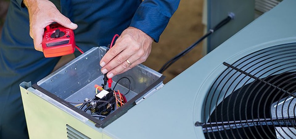 Electrician testing for an electrical current on an AC unit