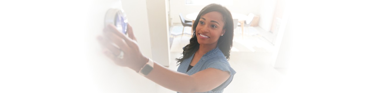 Woman adjusting a smart thermostat